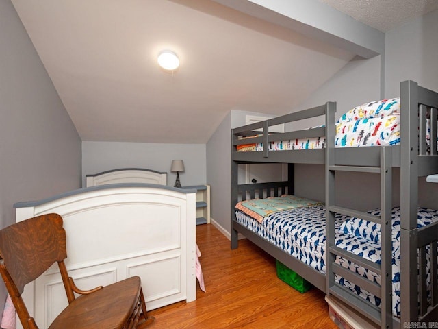 bedroom with wood finished floors and lofted ceiling