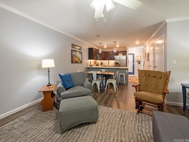 living room featuring a ceiling fan, baseboards, crown molding, and wood finished floors
