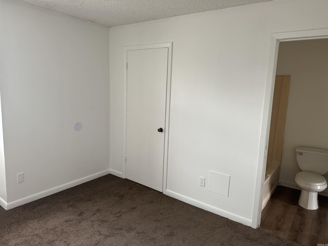 unfurnished bedroom featuring carpet floors, a textured ceiling, and baseboards
