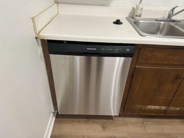 interior details with stainless steel dishwasher, dark brown cabinets, wood finished floors, and a sink