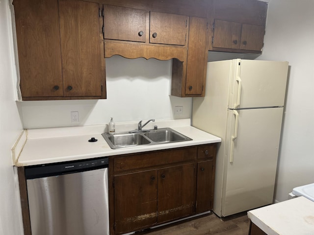 kitchen featuring stainless steel dishwasher, a sink, light countertops, and freestanding refrigerator