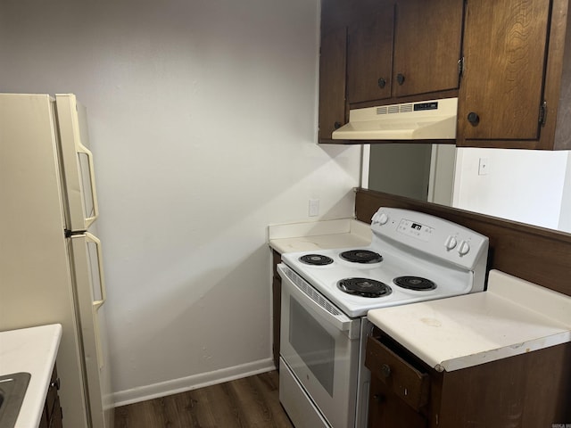 kitchen featuring white appliances, dark brown cabinetry, baseboards, under cabinet range hood, and dark wood-type flooring
