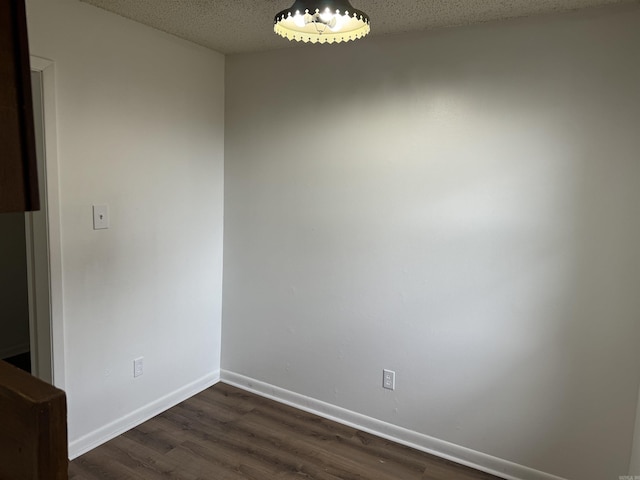 unfurnished dining area with baseboards, a textured ceiling, and dark wood-style floors