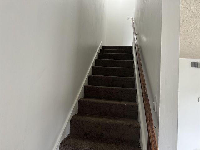 staircase with a textured ceiling and visible vents