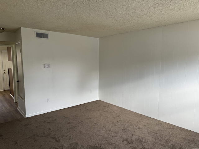 unfurnished room featuring dark colored carpet, a textured ceiling, and visible vents