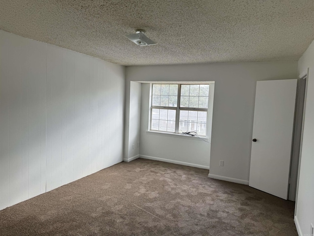 carpeted empty room featuring a textured ceiling
