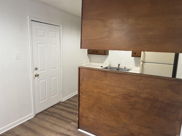 kitchen with dark wood finished floors, baseboards, a sink, and freestanding refrigerator