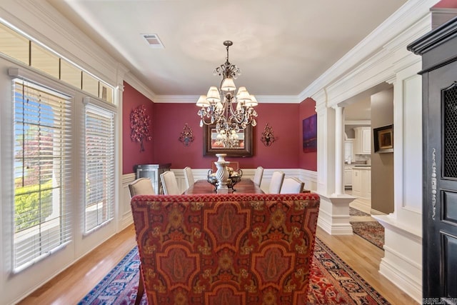 dining space with light wood-type flooring, decorative columns, visible vents, a chandelier, and ornamental molding