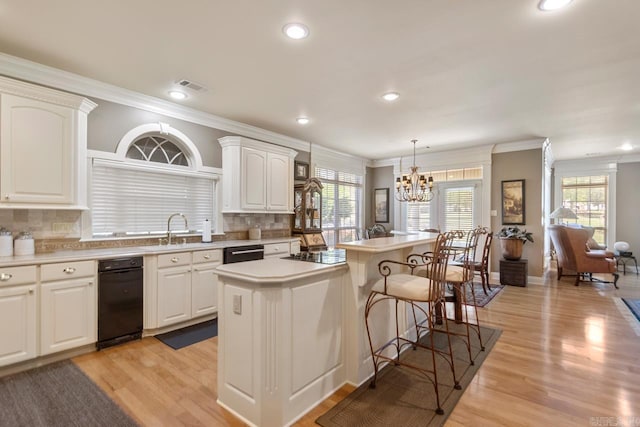 kitchen featuring an inviting chandelier, a breakfast bar, visible vents, ornamental molding, and a sink