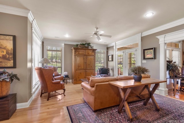 living area featuring light wood-style flooring, crown molding, baseboards, and a ceiling fan