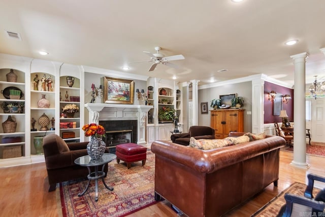 living area with ornamental molding, decorative columns, visible vents, and ceiling fan