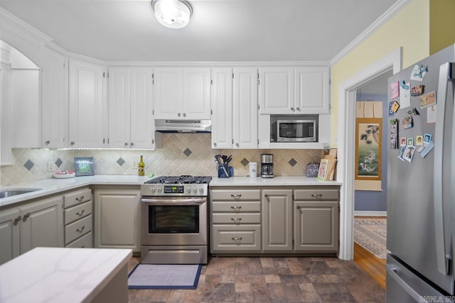 kitchen with under cabinet range hood, backsplash, appliances with stainless steel finishes, and light countertops
