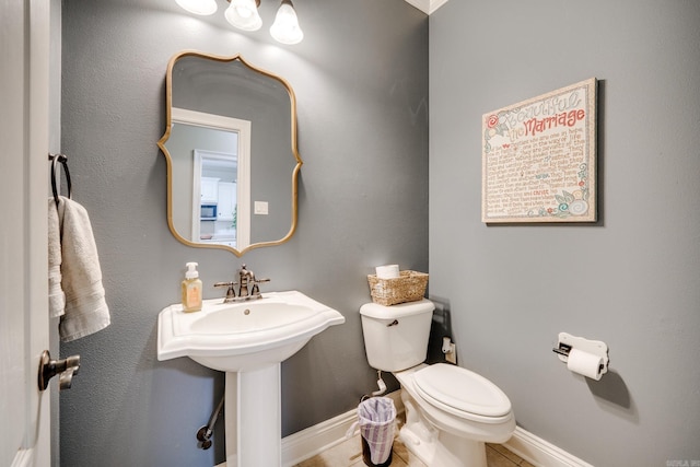 bathroom featuring tile patterned flooring, toilet, baseboards, and a sink