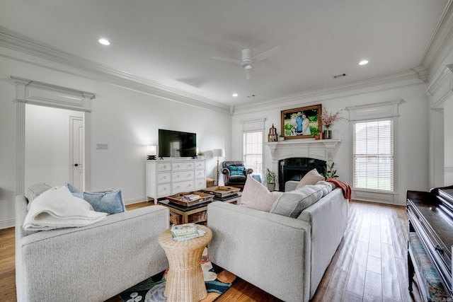 living room with visible vents, a premium fireplace, a ceiling fan, wood finished floors, and crown molding