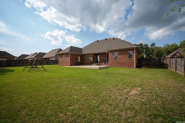 back of house with a patio area, a lawn, a shingled roof, a fenced backyard, and brick siding