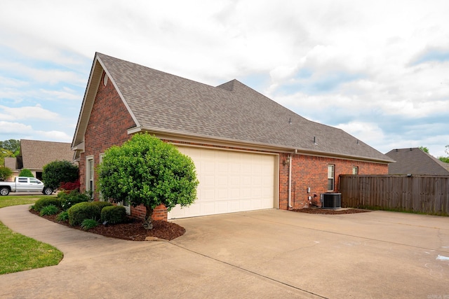 view of side of home featuring an attached garage, brick siding, roof with shingles, and driveway