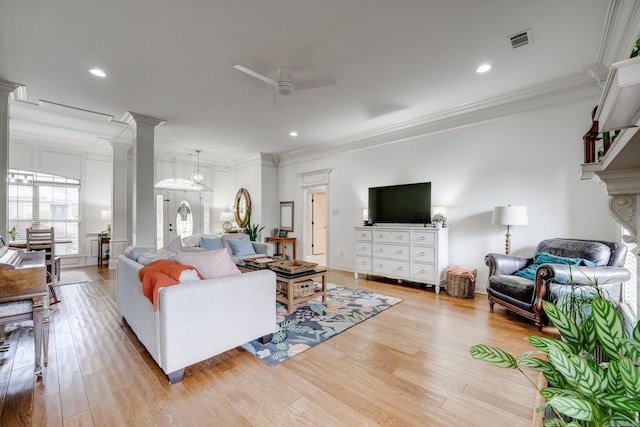living room featuring a ceiling fan, crown molding, visible vents, and light wood-type flooring