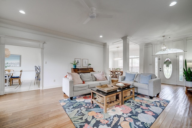 living area featuring a ceiling fan, ornamental molding, light wood-style floors, and ornate columns