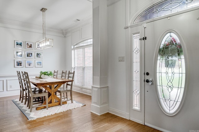 foyer with light wood-type flooring, a notable chandelier, and crown molding