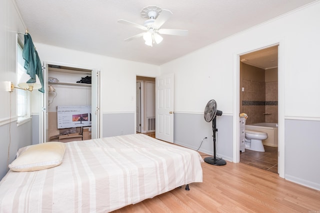 bedroom featuring ensuite bathroom, wood finished floors, a closet, and a ceiling fan