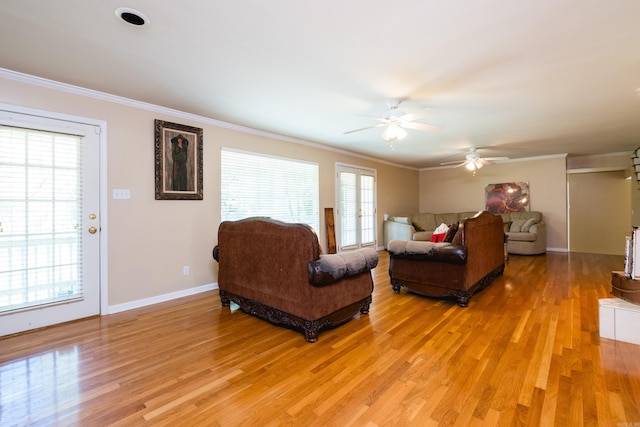 living area with light wood-type flooring, baseboards, ornamental molding, and ceiling fan