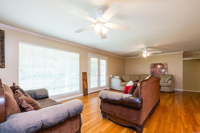 living area featuring light wood-type flooring, a ceiling fan, baseboards, and ornamental molding