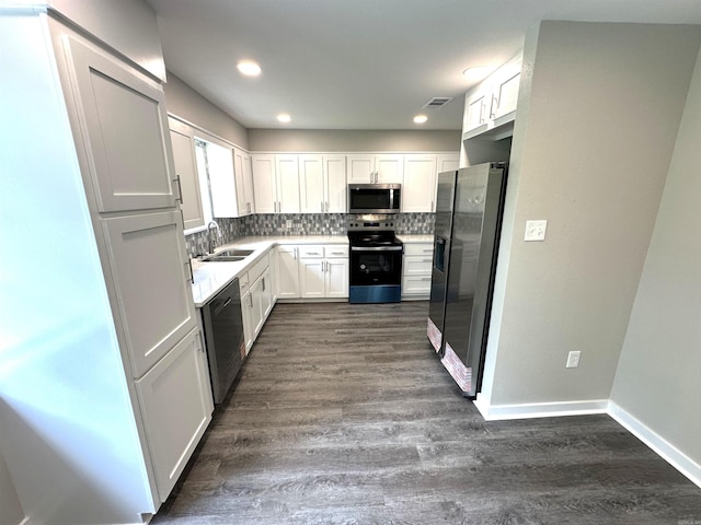 kitchen featuring appliances with stainless steel finishes, a sink, decorative backsplash, dark wood finished floors, and white cabinets