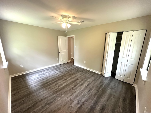 unfurnished bedroom featuring dark wood-type flooring, baseboards, a closet, and a ceiling fan