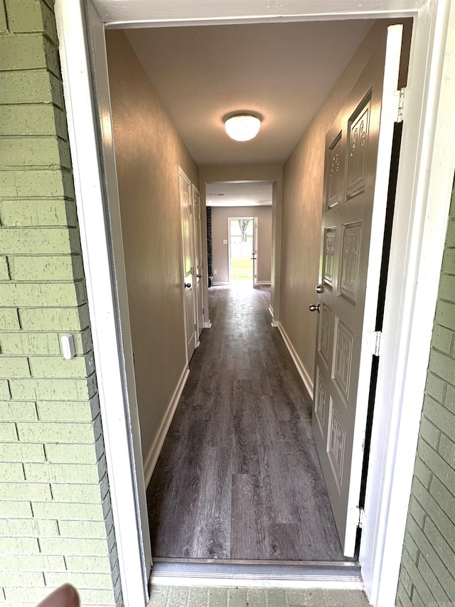 hall featuring dark wood-style flooring and baseboards
