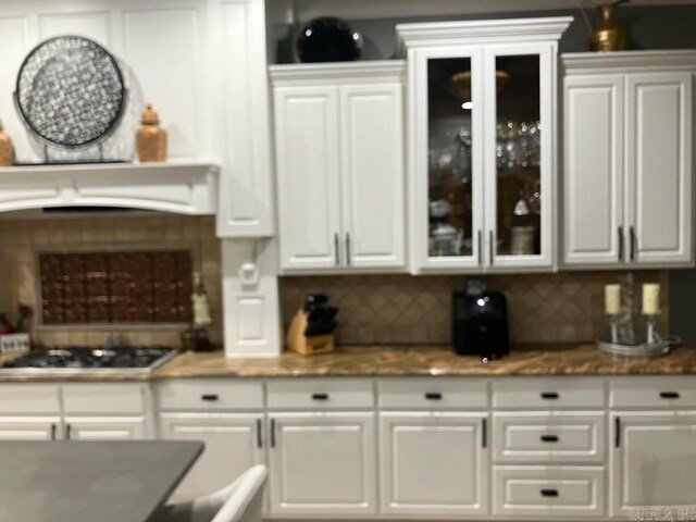 kitchen with stovetop, white cabinetry, and glass insert cabinets