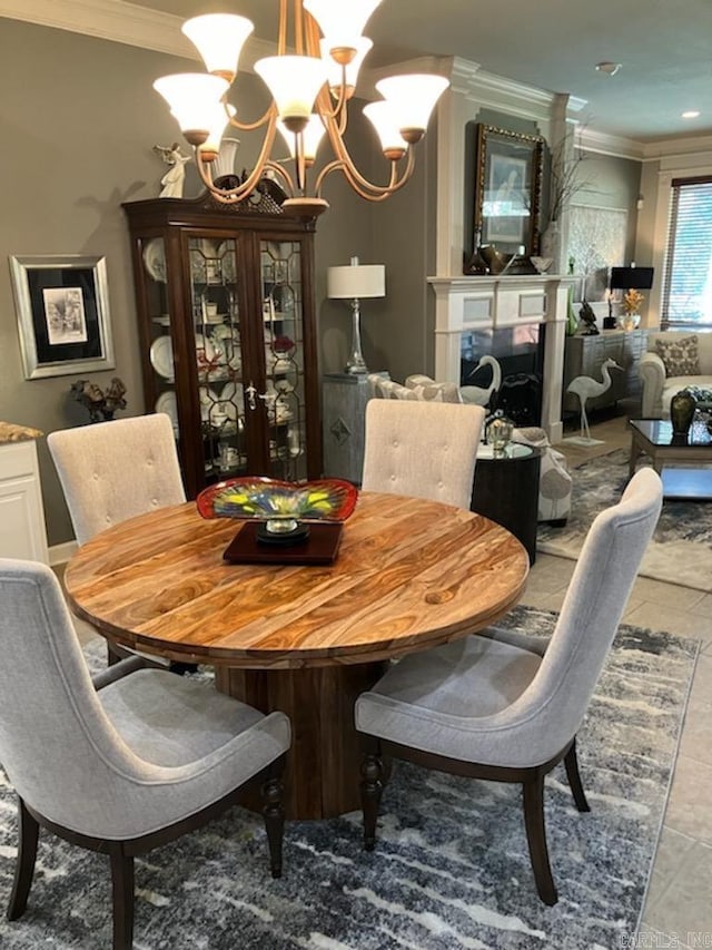 dining area featuring crown molding, a large fireplace, and a notable chandelier