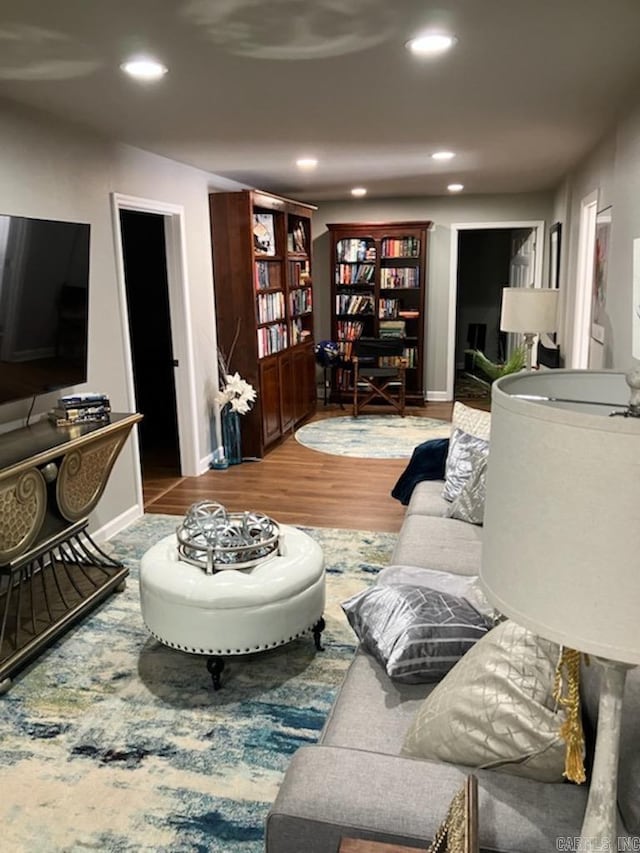 living area with baseboards, wood finished floors, and recessed lighting