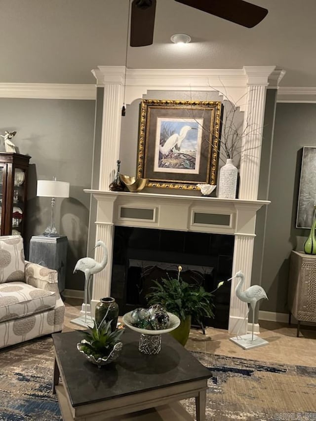 living area with baseboards, ornamental molding, a large fireplace, and ceiling fan