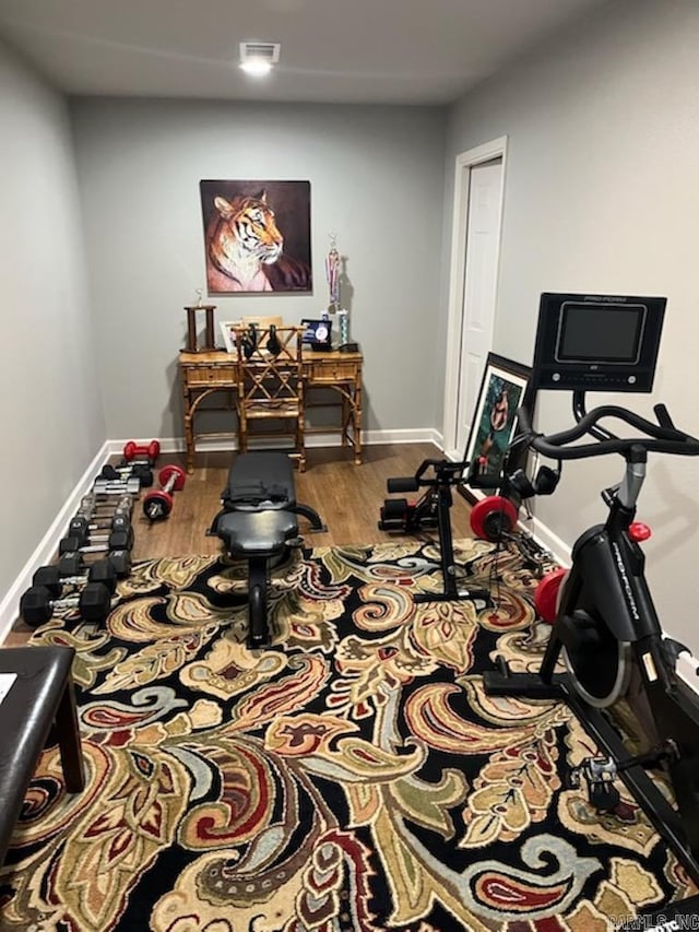 workout room with baseboards, wood finished floors, and visible vents