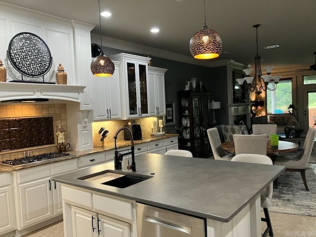 kitchen with decorative backsplash, appliances with stainless steel finishes, a sink, and a center island with sink