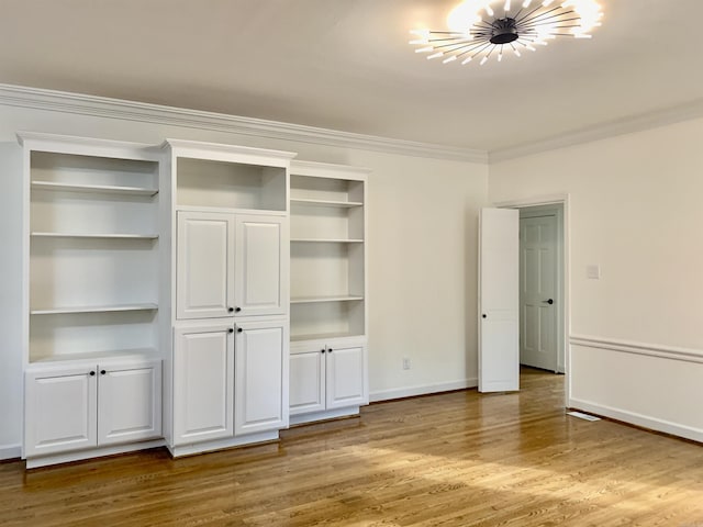 unfurnished bedroom featuring crown molding, wood finished floors, multiple closets, a chandelier, and baseboards