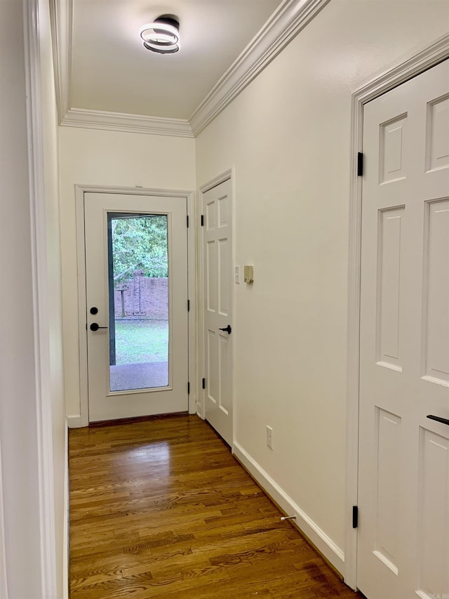 doorway with wood finished floors, crown molding, and baseboards