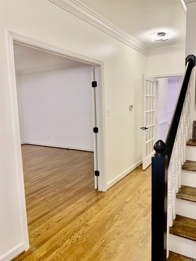 hall with baseboards, light wood-type flooring, stairs, and ornamental molding