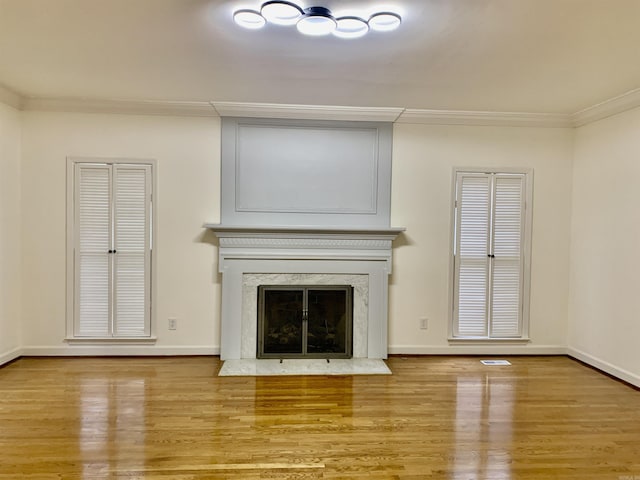unfurnished living room with a high end fireplace, baseboards, ornamental molding, and wood finished floors