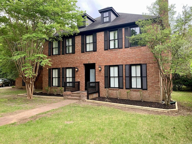 colonial home with brick siding and a front yard