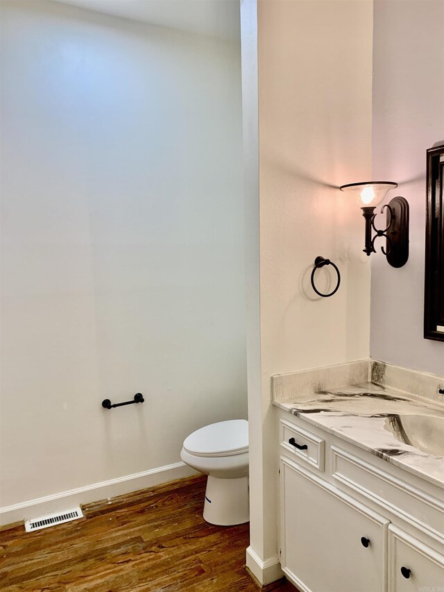 bathroom featuring wood finished floors, visible vents, toilet, vanity, and baseboards