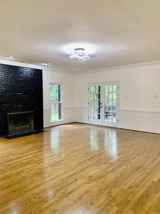 unfurnished living room with plenty of natural light, wood finished floors, a chandelier, and crown molding