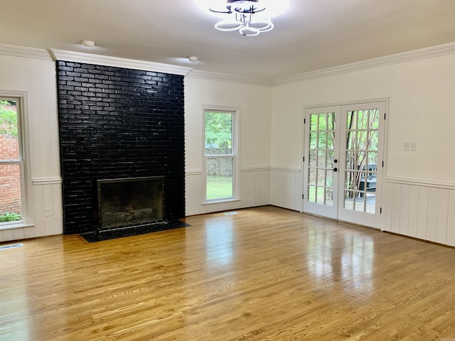 unfurnished living room featuring wainscoting, a healthy amount of sunlight, and wood finished floors