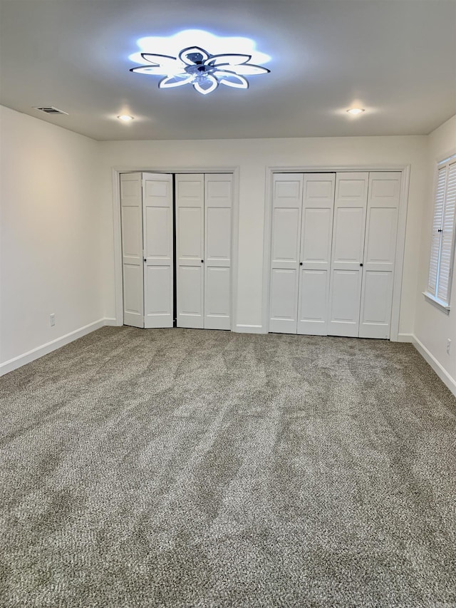 unfurnished bedroom featuring visible vents, multiple closets, baseboards, and carpet