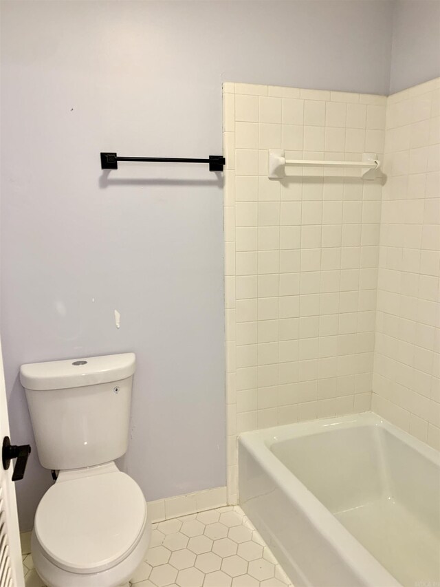 bathroom featuring washtub / shower combination, tile patterned floors, baseboards, and toilet