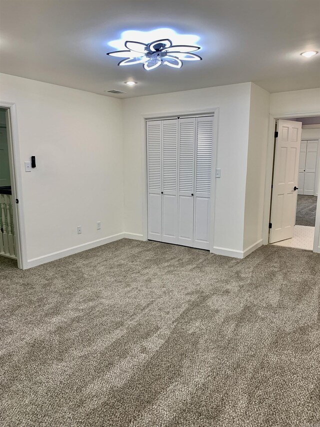 unfurnished bedroom featuring carpet floors, a closet, visible vents, and baseboards