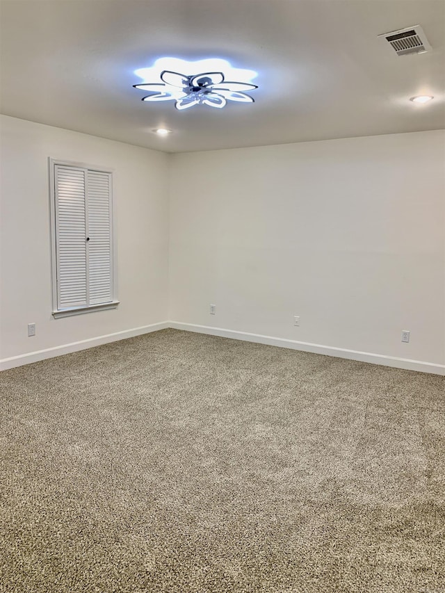 carpeted empty room featuring baseboards and visible vents