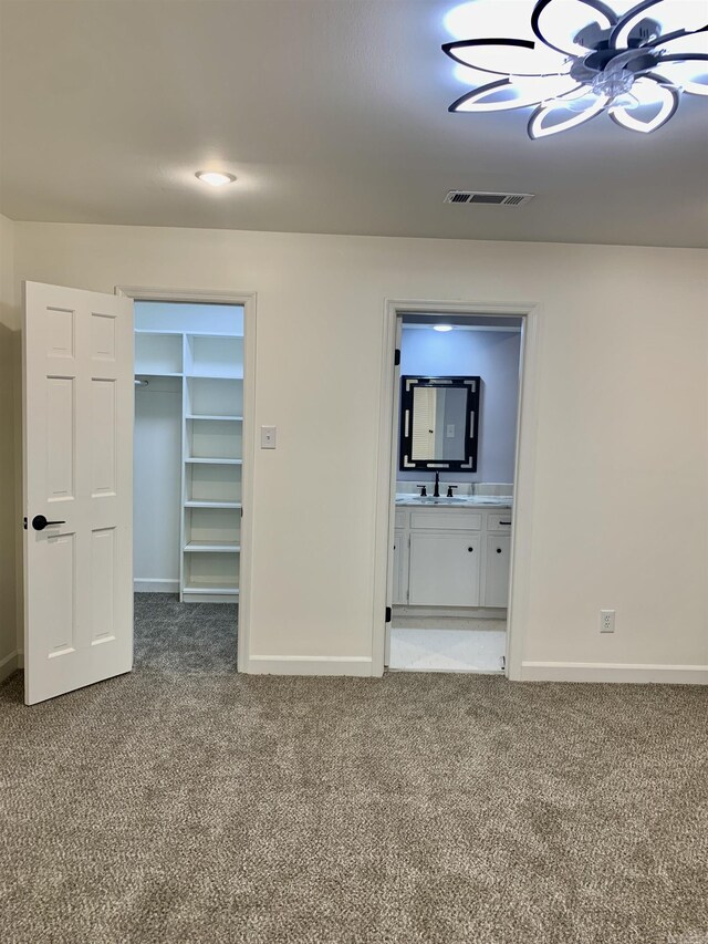 interior space with carpet floors, a ceiling fan, baseboards, and a sink