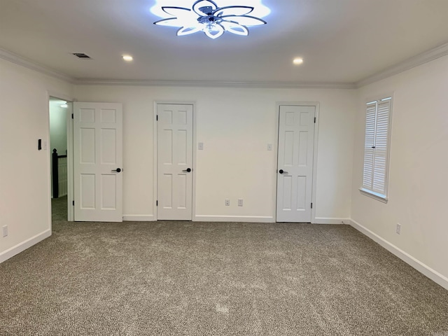 carpeted spare room featuring a notable chandelier, baseboards, ornamental molding, and visible vents