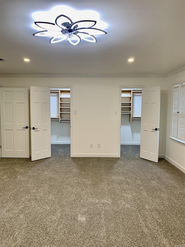 interior space featuring baseboards, carpet flooring, a spacious closet, and ornamental molding